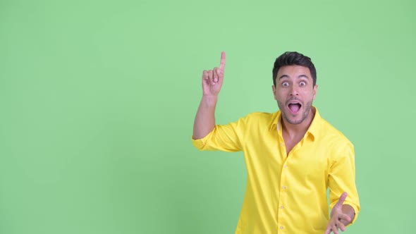 Happy Young Hispanic Businessman Pointing Up and Looking Surprised