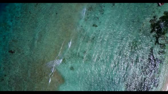 Aerial flying over landscape of idyllic resort beach holiday by aqua blue water with clean sand back