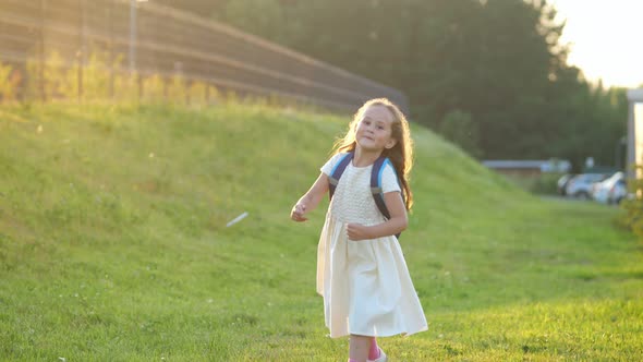 Elementary Schoolgirl Runs with Smile Jumping on Grass