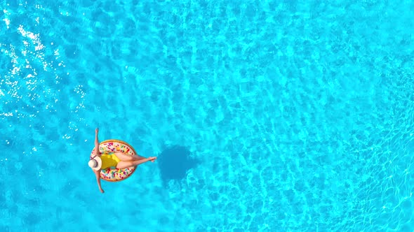 Aerial View of a Woman in Yellow Swimsuit Lying on a Donut in the Pool