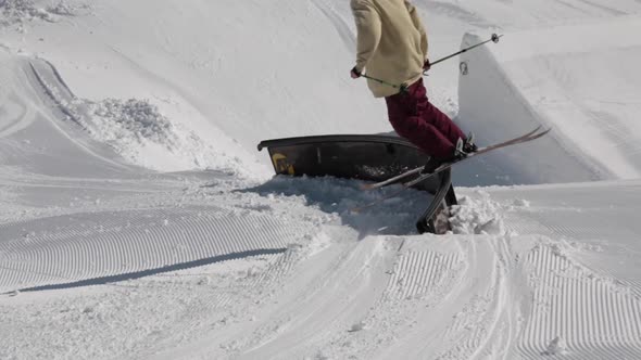 A young man skier performing grind tricks in terrain park.