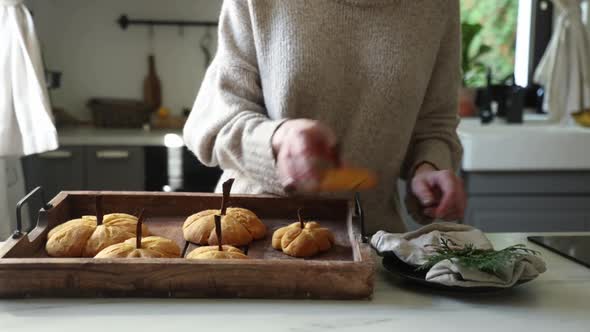 Woman shifts from tray to plate pumpkin cookies at kitchen