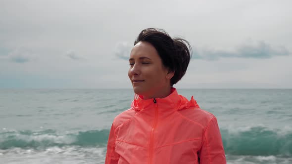 Portrait of young beautiful woman standing on edge of seashore