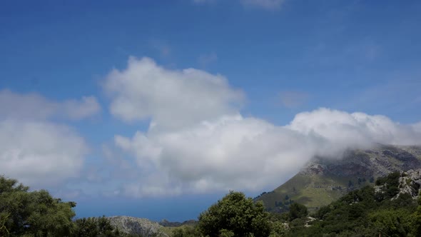 TIME LAPSE: Clouds passing by over mountains on a sunny island.