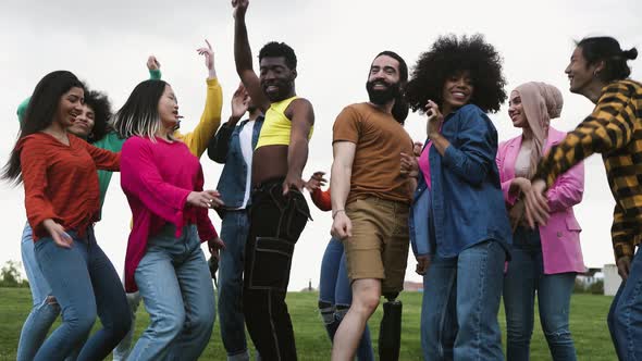 Young multiracial friends having fun dancing together in park - Friendship and diversity concept