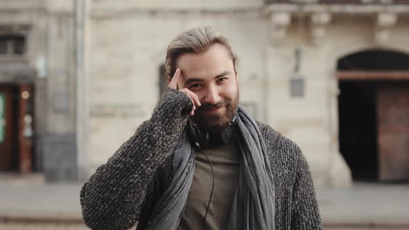 A Happy Bearded Man is Listening to Music and Walking Around the City Center