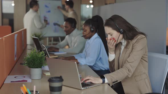 Woman in Headset Coughing While Working on Laptop