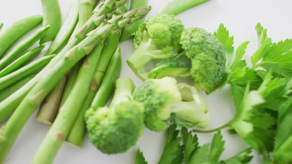 Video of close up of fresh green vegetables on white background