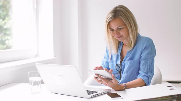 Businesswoman using digital tablet and laptop at home