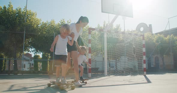 Mother Teach Her Children to Ride on Skate and Longboard on Summertime Vacation