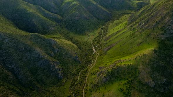 Winding river and road between green hills