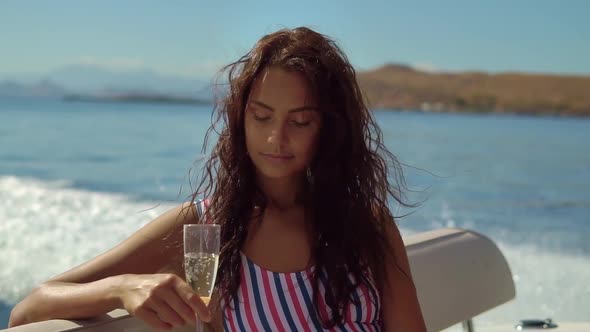 Close Up Shot of Attractive Young Dark Haired Woman Holding Champagne in a Hand Relaxing on Yacht