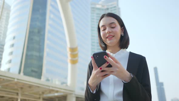 Asian young smart businesswoman using mobile phone chatting in the city enjoy telecommunication.