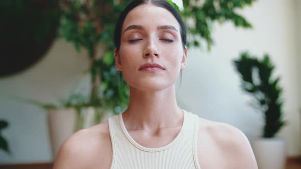 Sporty brunette woman looking at the camera while sitting in lotus position