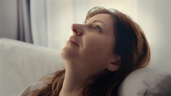 Happy Woman Puts Her Head on the Back of the Sofa and Closes Her Eyes Dreaming