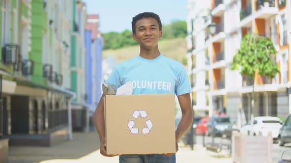 Happy Mixed-Race Teen Male Eco-Volunteer Holding Paper Box With Recycling Sign