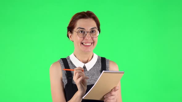 Portrait of Funny Girl in Round Glasses Is Thinking, Then Happy Writing with Pencil in Notebook