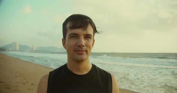 Portrait of a Young Caucasian Man Looking Into the Camera Along the Backdrop of the Beautiful Sea