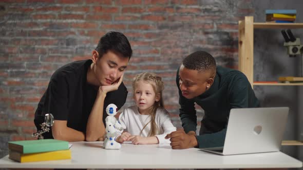 Little Girl with Science Teachers Look at Toy Robot on Table