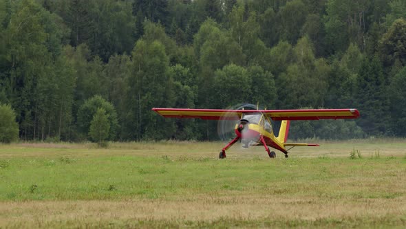 Small Bright Yellowred Civilian Small Aircraft Accelerates Across Field and is Ready to Take Off