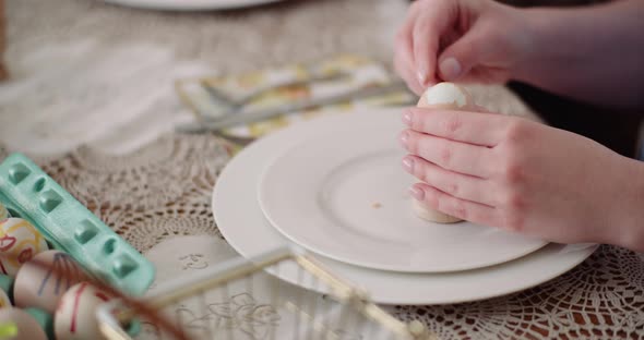 Woman Peeling Egg on Plate