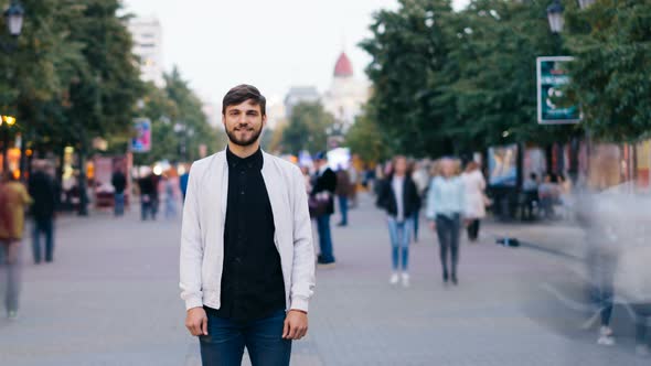 Time-lapse of Confident Man in Jeans and White Jacket Standing Alone in Street in City and Looking