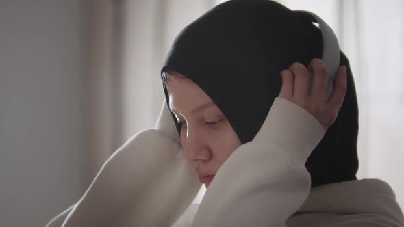 Pretty Woman in Hijab Puts Big Headphones on Her Head