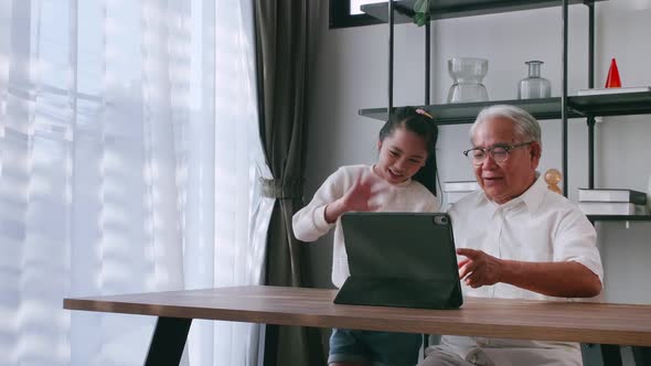 An Asian grandfather and granddaughter spending time together in the living room.