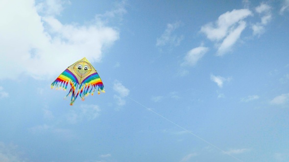 Colorful kite flying against the blue sky with clouds