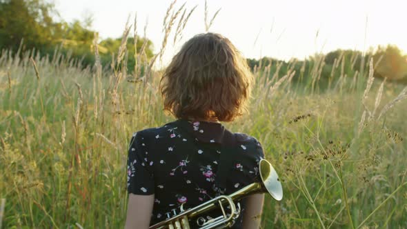 a Young Woman with Curly Hair Walks Through the Grass Flirting with Looking Into the Camera and