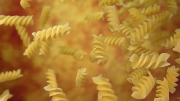 Dry Pasta Fusili Flying Diagonally on a Yellow Ochre Background