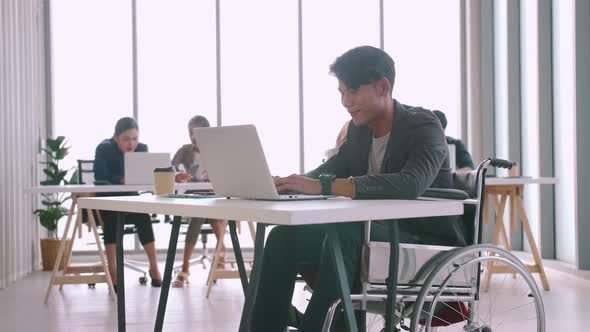 A disabled company employee is able to work happily with colleagues in the office.