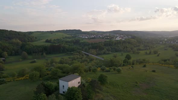 Little white brick hut on the top of a green hill in Germany's countryside. Aide angle aerial boom