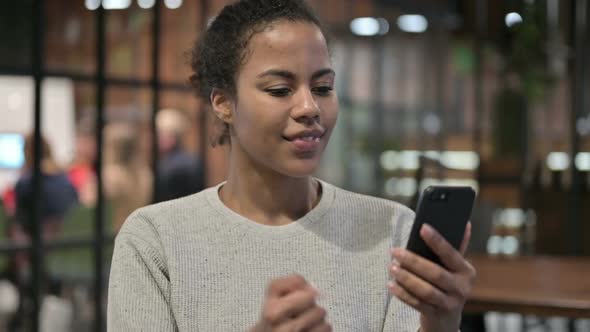 African Woman Celebrating Success on Smartphone
