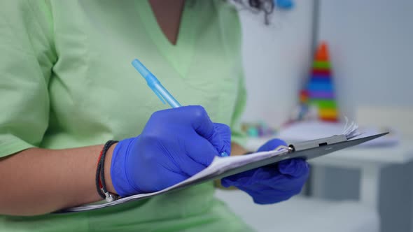 Closeup Medical History in Female Hands with Unrecognizable Doctor Writing with Pen