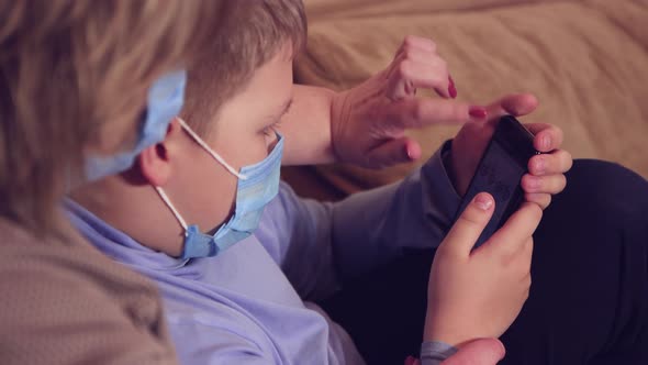 Mom and Son in Medical Masks are Shopping Online While Sitting on the Couch