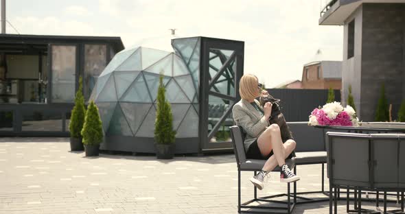 Young Casually Dressed Woman Sitting at Cafe with Her Bulldog Puppy