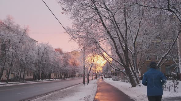 Running Man in Winter City Morning at Sunrise. Winter Sports Athlete Doing Cardio Exercise in Slow