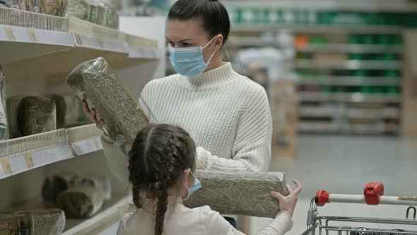 Mom and Daughter 67 Years Old Choose Hay for a Rabbit in the Pet Section of the Supermarket