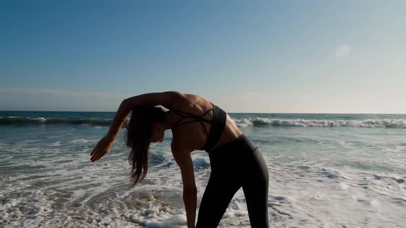 Athletic woman at the beach stretching and relaxing after her workout