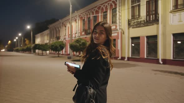 A Spectacular Young Girl Goes in the Evening Through the Historic Quarter of the City and Leafs