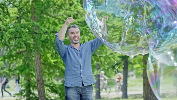 Man Launching Huge Soap Bubble with Tri-Strings Wand