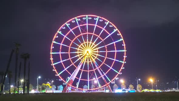 Ferris Wheel Spins at Night with Colored Lights