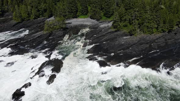 Canada's wild west coast shoreline during sunny day in spring of 2021. Huge untamed waves crashing o