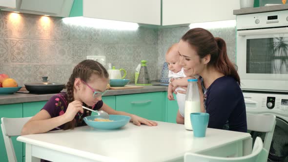 Girl Eating Corn Flakes with Milk at Kitchen Table