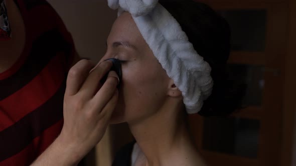 Visagiste applying cream on face of woman