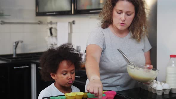White Mother with Her Black Mixed Daughter Making Dough on the Kitchen