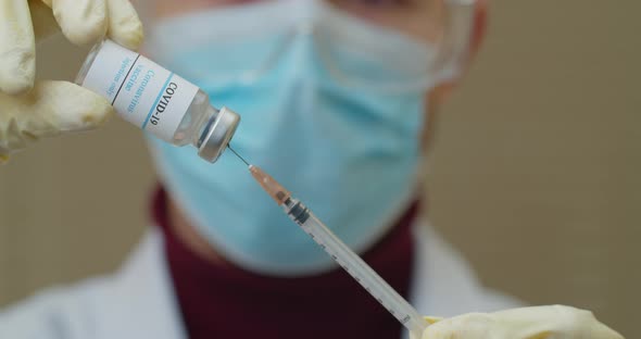 Medical with Face Mask Filling a Syringe with Vaccine