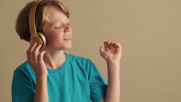 A pleased little boy is listening the music using headphones