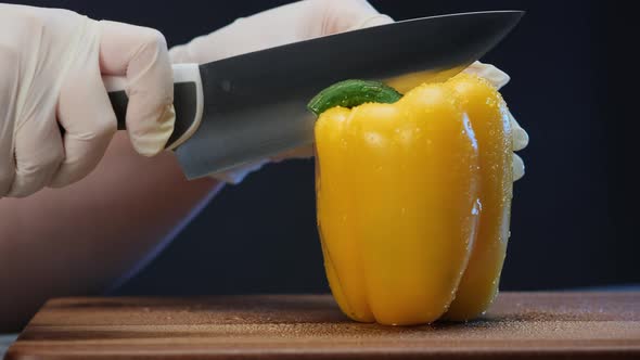 Person in White Gloves Cuts Yellow Bell Pepper with Knife